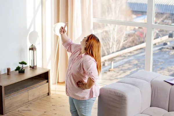 Freudig gut aussehende Frau blickt in die Smartphone-Kamera — Stockfoto