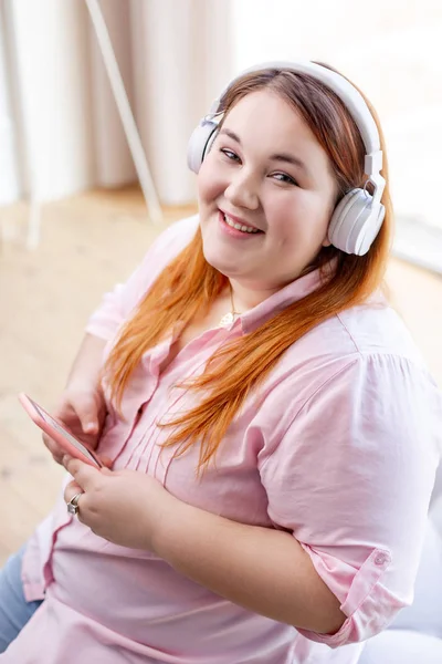 Mujer alegre encantada sentada con su teléfono inteligente —  Fotos de Stock