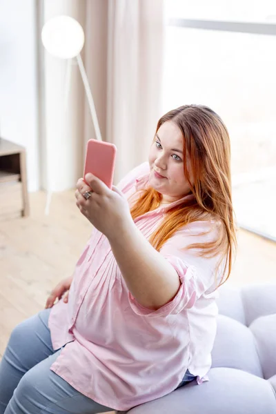 Positive Frau hält ihr Smartphone in der Hand — Stockfoto