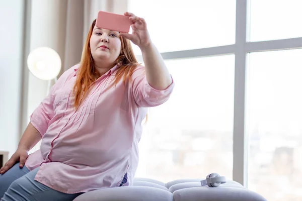 Mujer positiva de buen aspecto mirando a sí misma en la pantalla — Foto de Stock