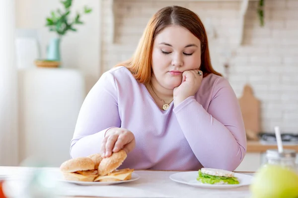 Mujer regordeta sin alegría pensando en la hamburguesa — Foto de Stock