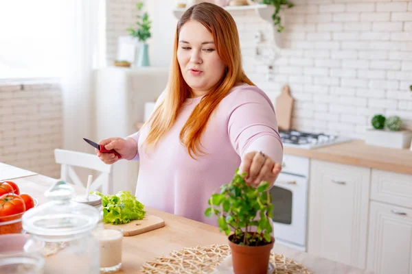 Trevlig fyllig kvinna som tar ett löv från växten — Stockfoto