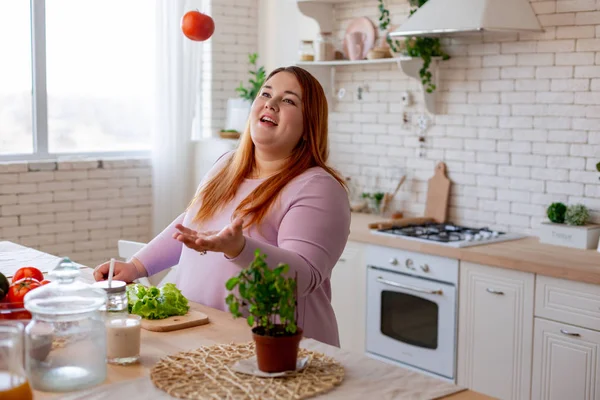 Радостная позитивная женщина играет с помидорами — стоковое фото