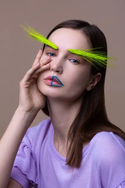 Blue-eyed model with blue lines in lips posing with spikelet