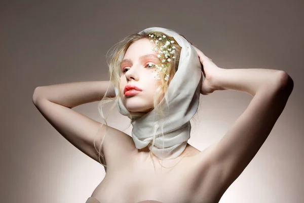 Blonde model with wavy hair posing in bra with silk scarf on head
