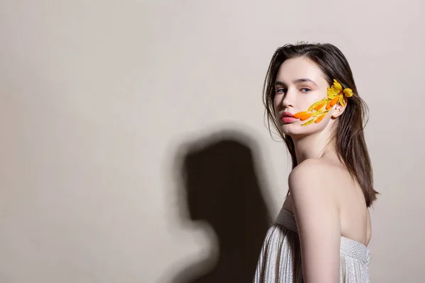 Modelo posando em vestido de ombro aberto com penas no rosto — Fotografia de Stock