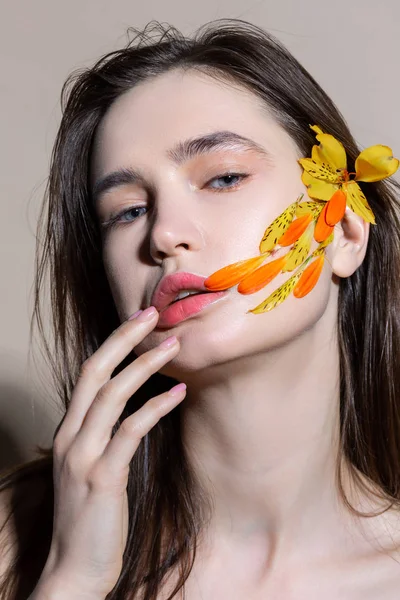 Aantrekkelijk model met bloem in haar aan te raken haar lippen terwijl poseren — Stockfoto