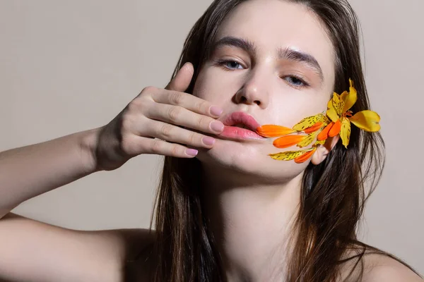 Modelo de ojos azules con maquillaje natural que tiene pétalos de flores en la cara —  Fotos de Stock