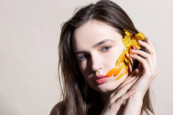 Modelo de ojos azules con flor naranja en cabello liso oscuro —  Fotos de Stock