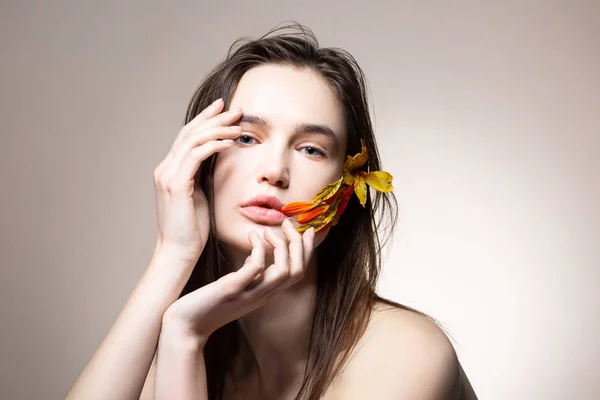 Modelo atractivo tierno con flor naranja en cabello oscuro — Foto de Stock