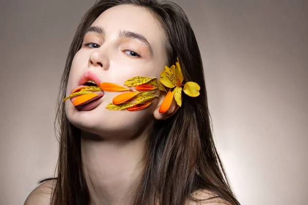 Modelo con maquillaje natural posando con pétalos en la boca —  Fotos de Stock
