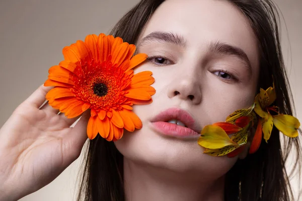 Model with no makeup posing with flower petals on face