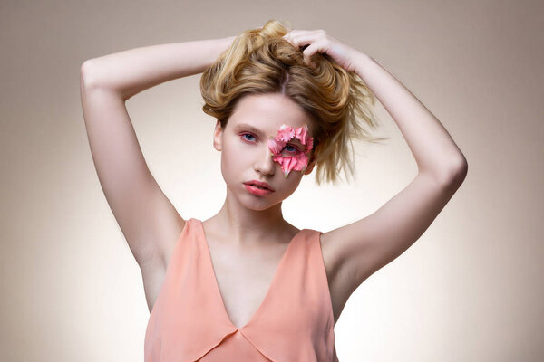 Blue-eyed model with flower petals around eye touching her hair