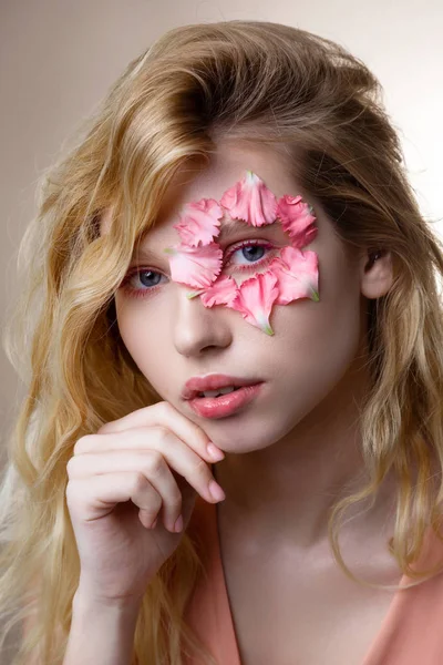 Mujer tierna de ojos azules con pétalos rosados alrededor de su ojo — Foto de Stock