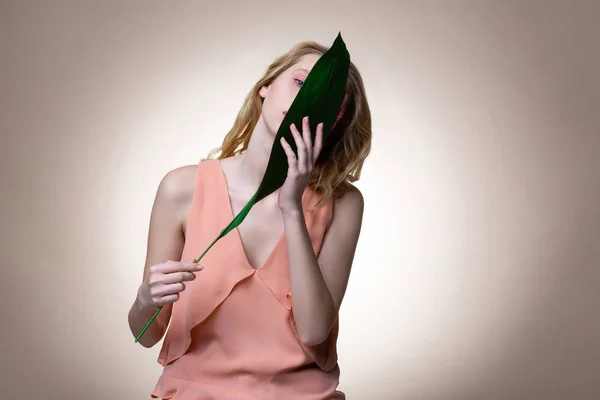大きな緑の葉を持つスタイリッシュなドレスを身に着けているテンダーモデル — ストック写真