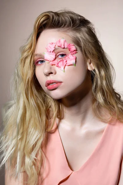 Modelo con increíbles ojos azules y cabello ondulado con pétalos alrededor del ojo —  Fotos de Stock