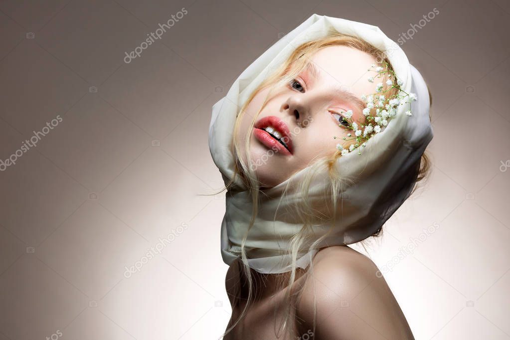 Young blue-eyed model posing with white silk scarf on head