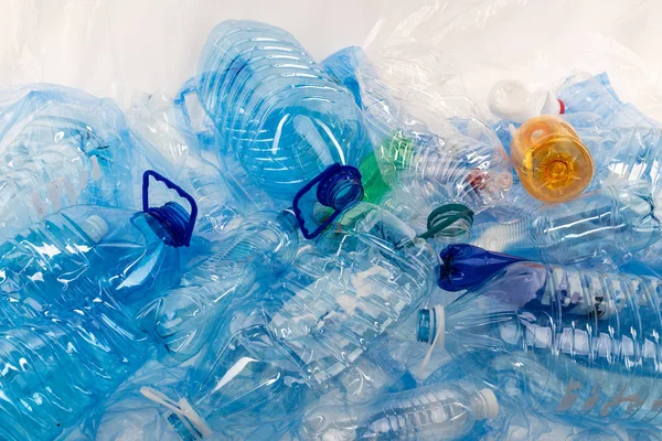 Garrafas de diferentes tamanhos e cores sendo colocadas juntas em esteira de plástico azul — Fotografia de Stock