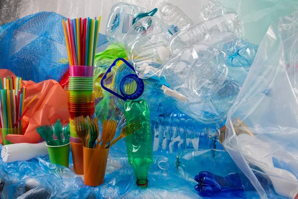 Färgglada plast gafflar placerade i plast kopp och stående nära gäng sopor — Stockfoto