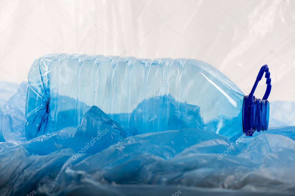 Empty clear liquid bottle placed in garbage and being thrown away