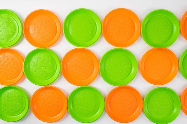Plaques jetables colorées vert vif et orange disposées en rangées — Photo
