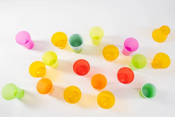 Různé světlé a barevné plastové šálky stojící na bílém povrchu — Stock fotografie