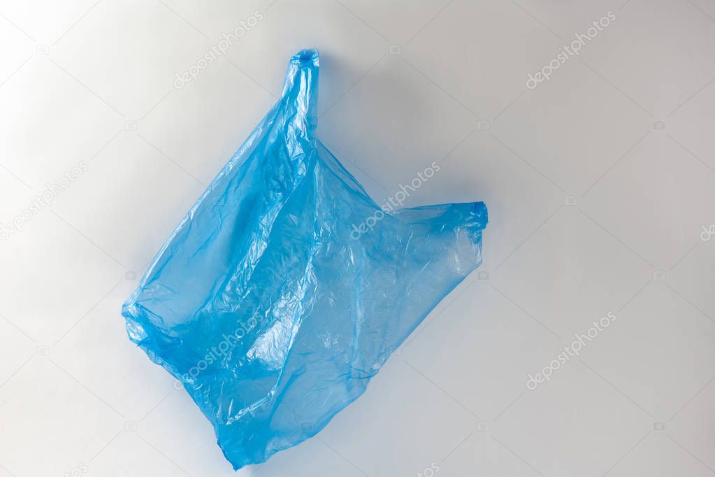 Used empty blue shopping bag being wrinkled and thrown in nature