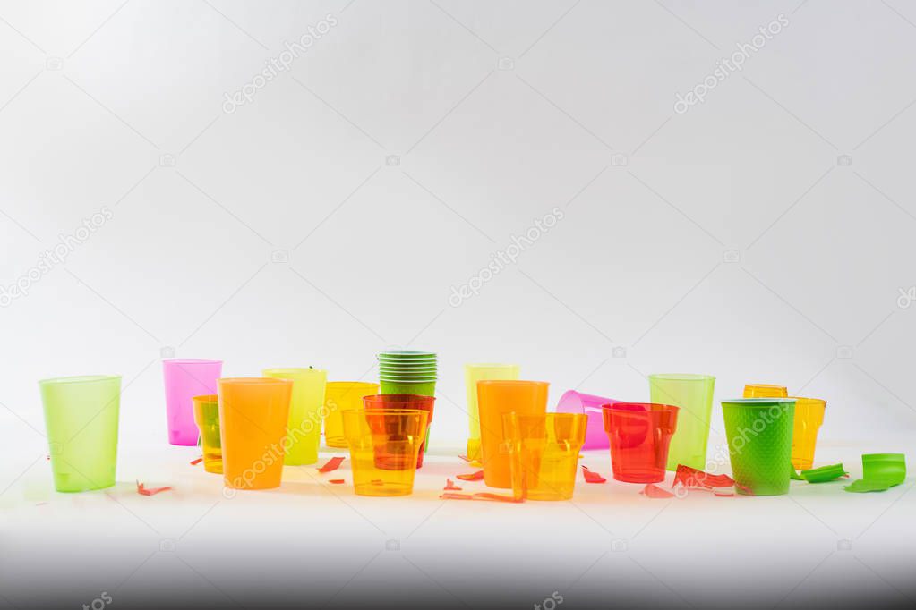 Colorful bright plastic cups standing with broken pieces around