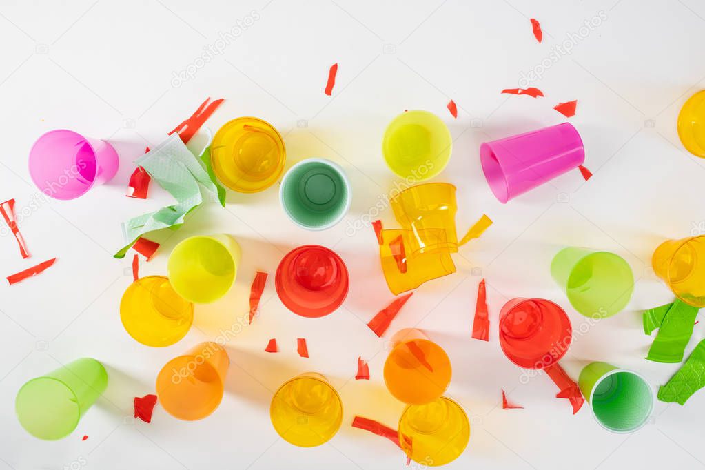 Sharp broken pieces of plastic cups lying on white surface