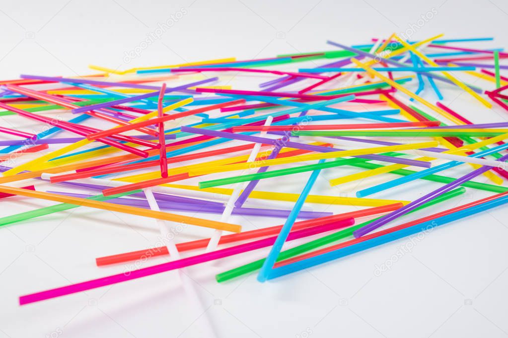 Colorful and toxic straws lying on the white surface