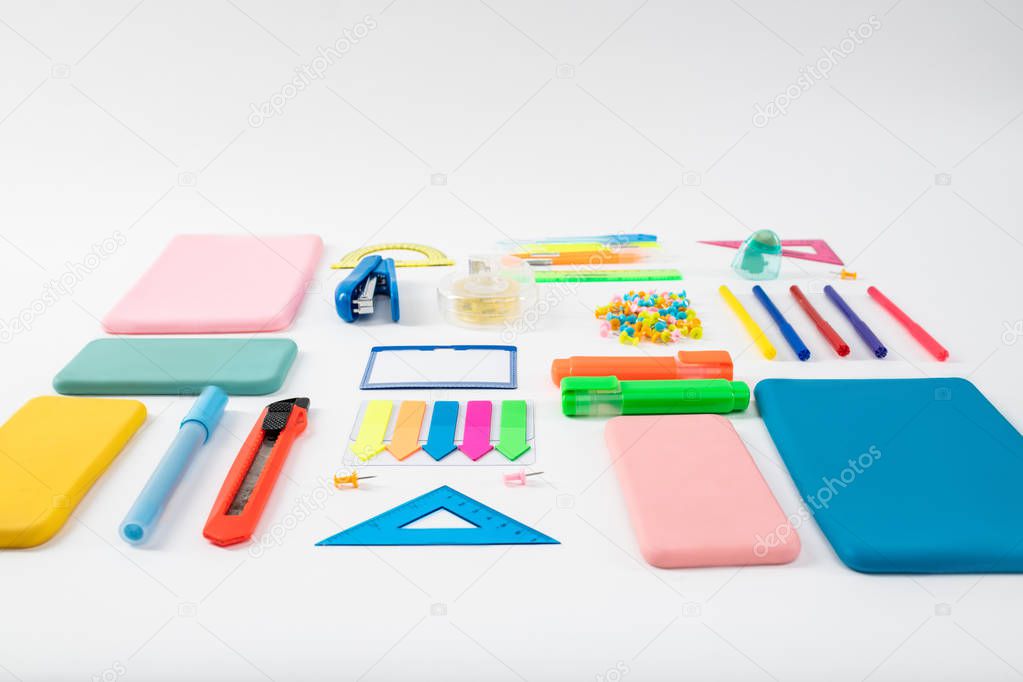 Bunch of colorful bright stationary and gadget cases lying on the white surface