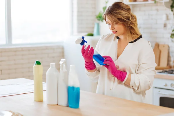 Serieuze jonge vrouw die een fles neemt met reinigingsmiddel — Stockfoto