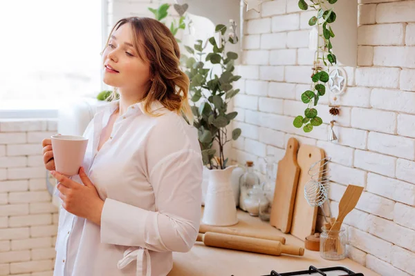 Mooie dromerige vrouw staande in de keuken — Stockfoto