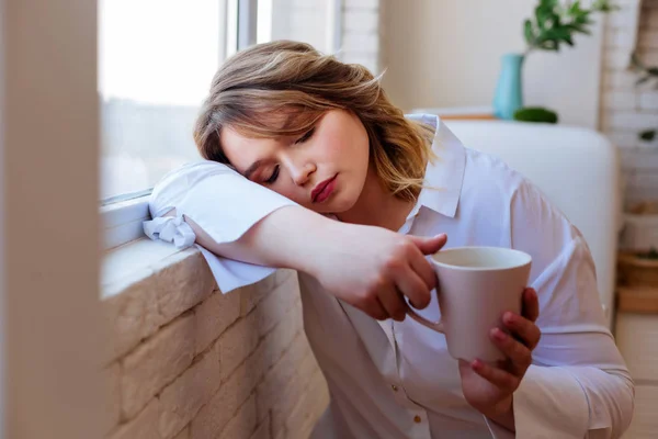 Милая уставшая женщина засыпает с чашкой чая — стоковое фото