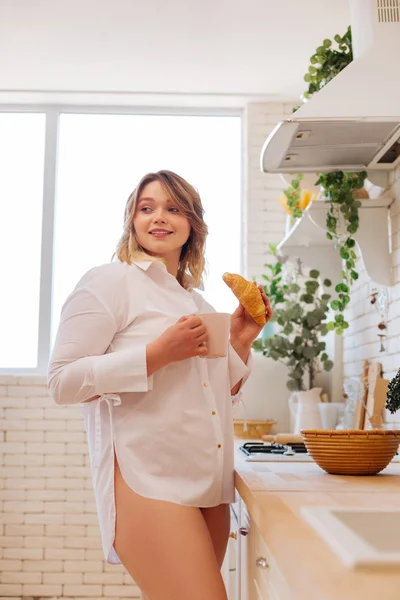 Vacker trevlig kvinna som har kaffe med en croissant — Stockfoto