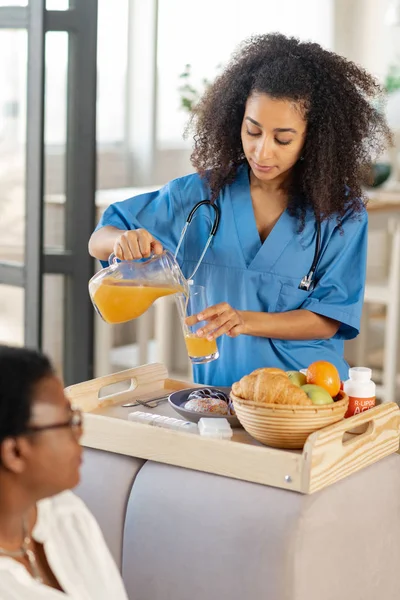 Lockigt mörkhyade sjuksköterska förbereder frukost för patienten — Stockfoto