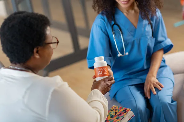 Patient med kort hår tar piller från sjuksköterska i blå uniform — Stockfoto