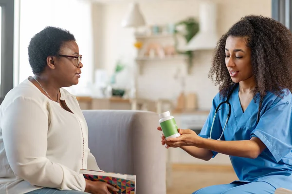 Dark-skinned woman with short hair talking to nurse bringing pills — Stock Photo, Image