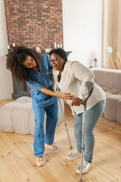 Private nurse helping aged woman after leg surgery at her home