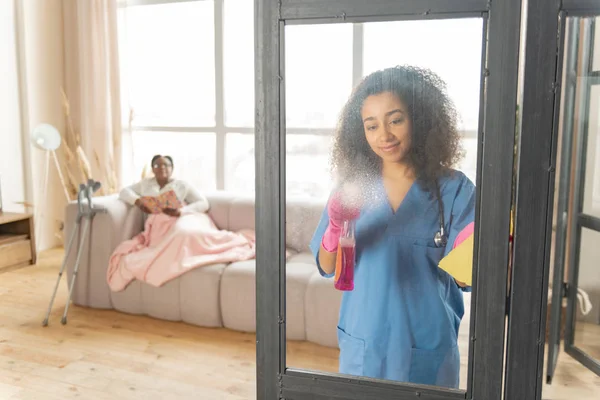 Infermiera pulire la porta di vetro nel soggiorno del paziente — Foto Stock