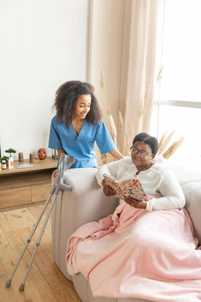 Zorgzame verpleegster komt naar de vrouw liggend en leest het boek — Stockfoto