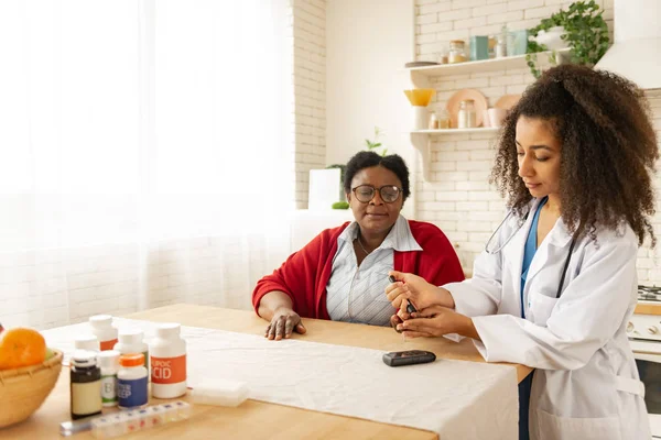 Ung sjuksköterska som tar blodprov på kvinna som har diabetes — Stockfoto