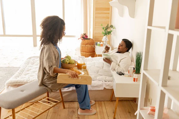 Paciente acostado en la cama y disfrutando del desayuno hablando con la enfermera —  Fotos de Stock