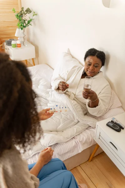 Paciente acostado en la cama y bebiendo agua después de tomar medicamentos —  Fotos de Stock