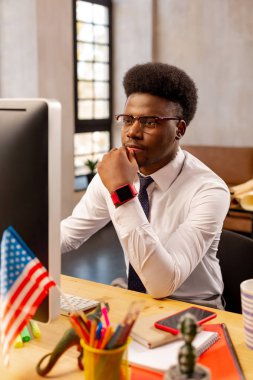 Genç Afrikalı Amerikalı adam ofiste oturuyor.