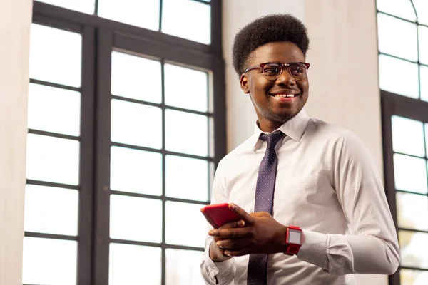 Hombre seguro positivo de pie con su teléfono móvil — Foto de Stock