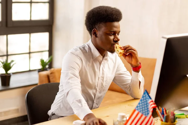 Sério afro-americano mordendo um sanduíche — Fotografia de Stock