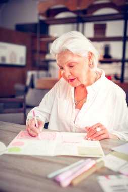 Gri saçlı yaşlı bayan boş zaman sahip bazı resimler boyama