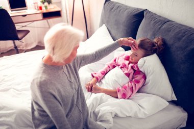 Büyükanne, yatakta yatarken hasta hissederek küçük kızına geliyor.