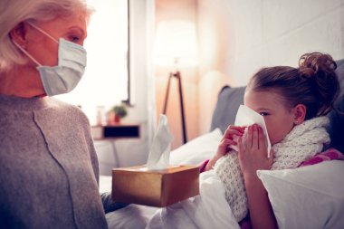 Büyükanne burun bazı peçete ile torunu veren